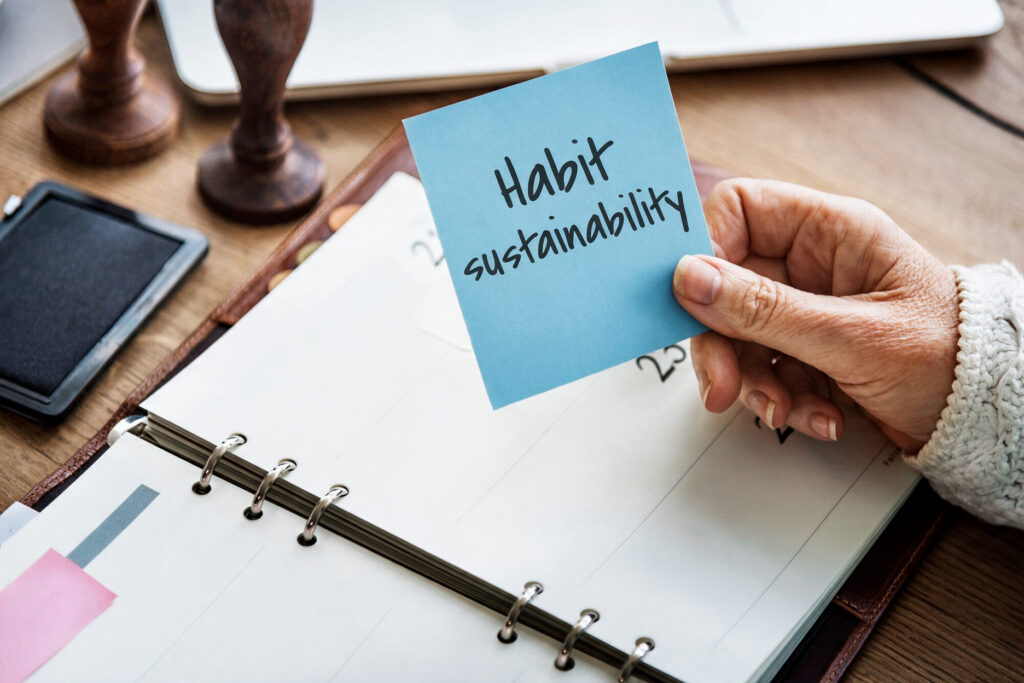 Woman holding a sticky note that says habit sustainability